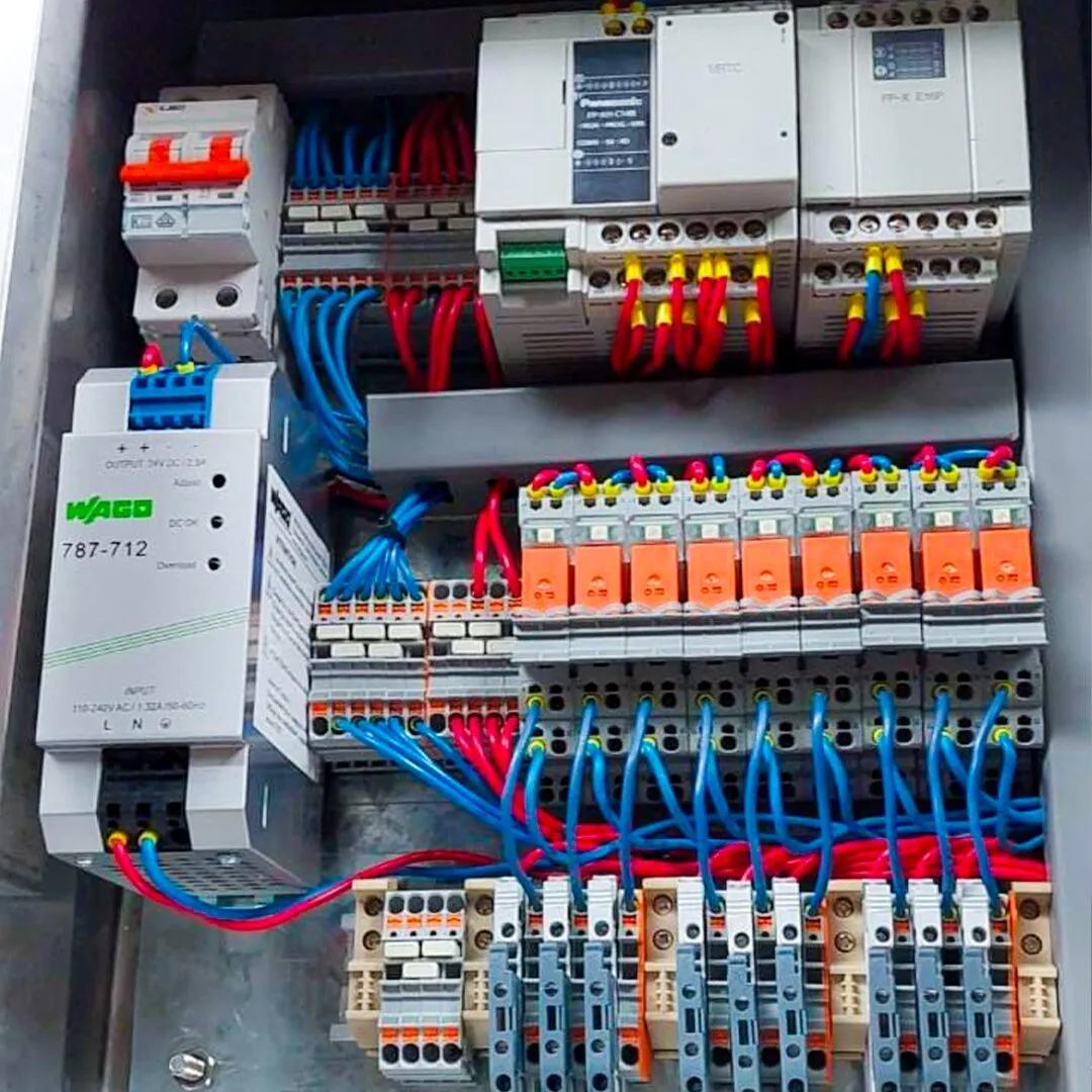 PLC y módulos de control cableados dentro de un tablero