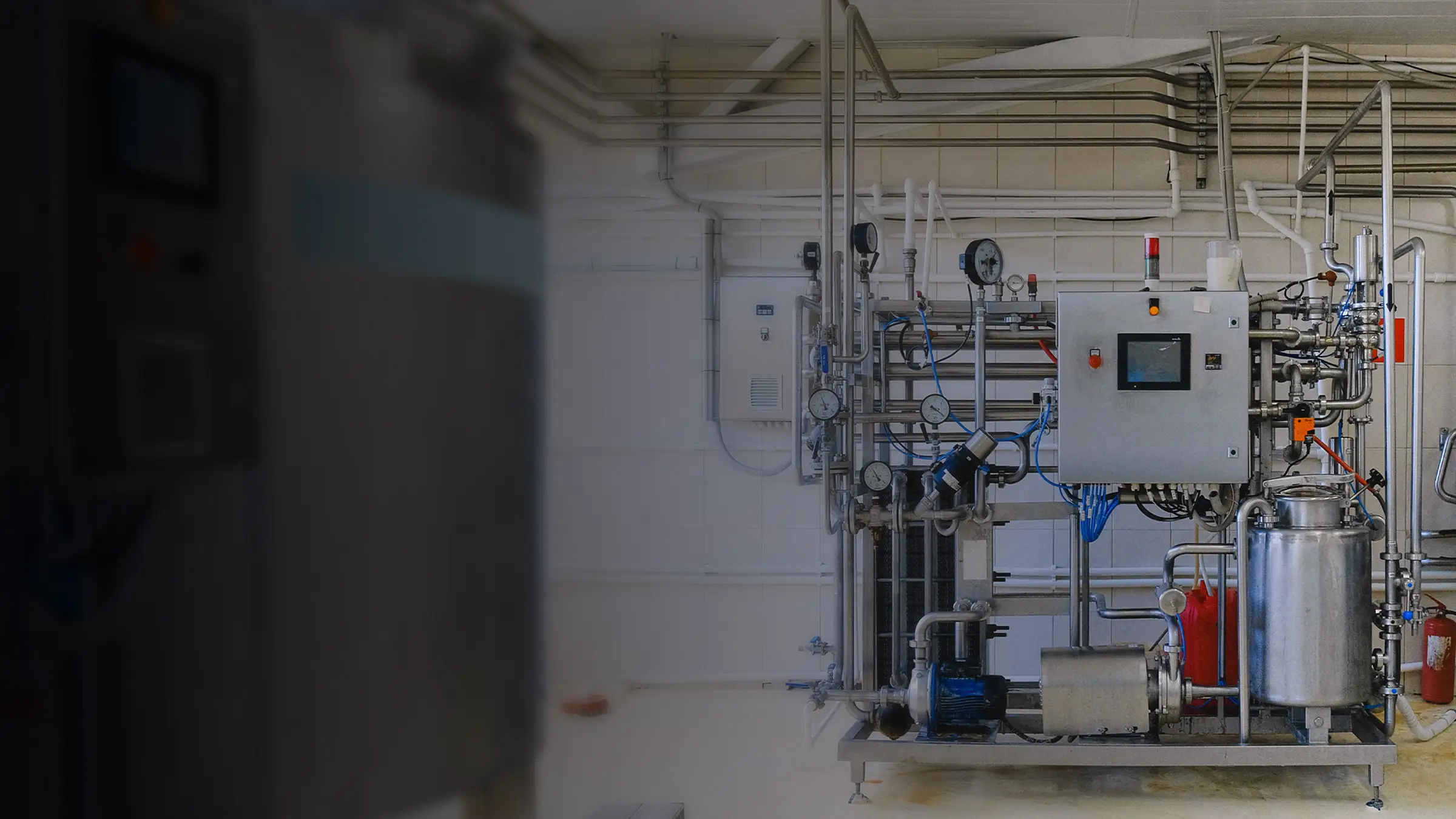 Línea de proceso industrial con tablero de control y tuberías en acero inoxidable